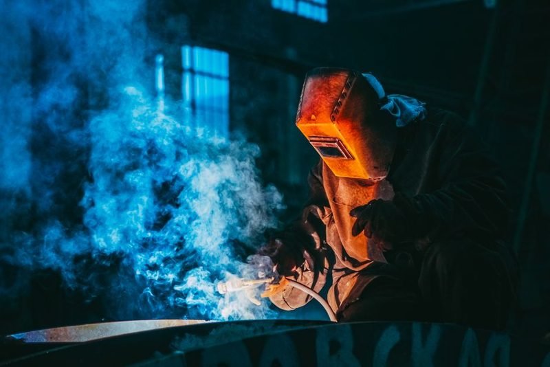 Welder in full gear working under shop lighting.